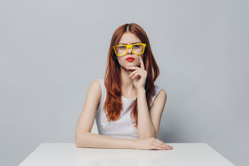 Serious Caucasian woman sitting at table wearing yellow eyeglasses