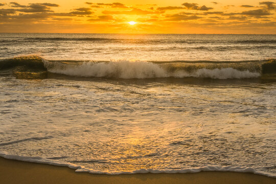 Calm Ocean Wave Breaking Onto Sandy Beach at Sunrise