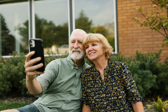 Smiling senior couple taking selfie in backyard
