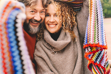 Portrait of young mature couple smiling and enjoying leisure activity together under a colorful...
