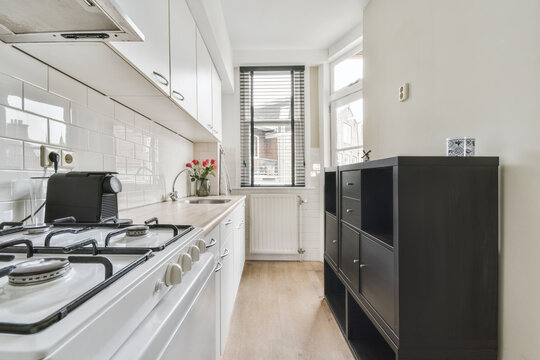 Stove and fridge in kitchen with white furniture in light apartment