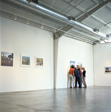 Group of people looking closely at photograph in art gallery