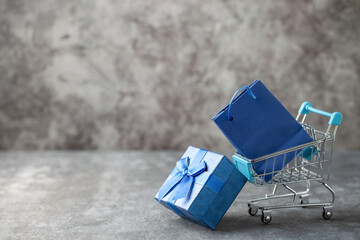 Mini cart with blue paper bag and gift box on dark background. 11.11 single's day sale concept. Copy space