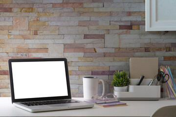 Home office laptop computer, picture frame, houseplant and stationery on white table. Modern workplace.