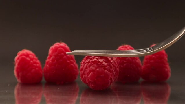 Crushing a raspberry with a fork on a black background