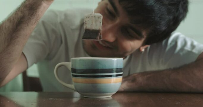 drug, addiction - stoned young man smiles staring at the tea bag he rocks