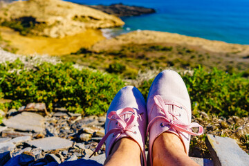 Naklejka premium Female legs in sneakers against coast landscape, Spain.