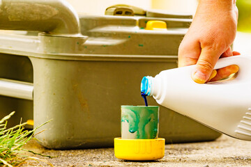 Man serving caravan, tank toilet cassette in dump station.