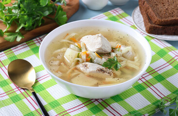 Soup with chicken, vegetables and egg noodles in a white bowl