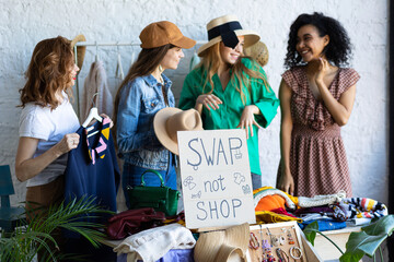 Young women at swap home party - clothes, shoes, bags, jewellery exchange between friends. Zero...