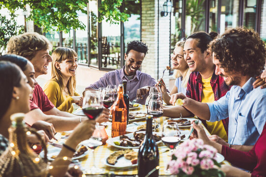 Happy multiracial family having bbq dinner party outside - Group of friends dining at garden restaurant - Young people enjoying lunch break together - Food and beverage lifestyle concept