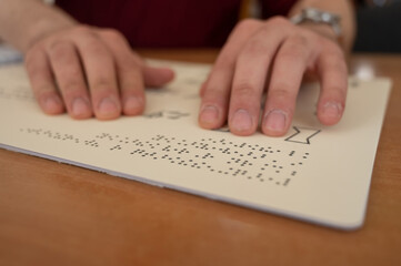 Visually impaired man reading a braille book. 