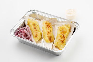 Pita with potato on it with round onion, sauce, in tray on black stone background and white background