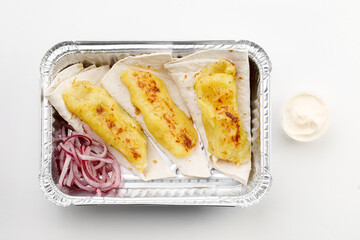 Pita with potato on it with round onion, sauce, in tray on black stone background and white background