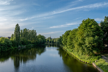 landscape shot of the river trave in luebeck with green trees on the bank and a blue sky
