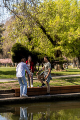 Group of three young friends having fun in the park near the park lake