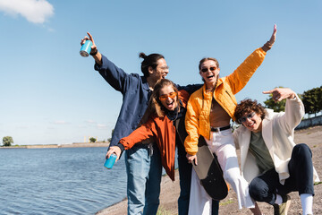 happy man showing rock sign near multicultural friends with skateboard and soda cans. © LIGHTFIELD STUDIOS