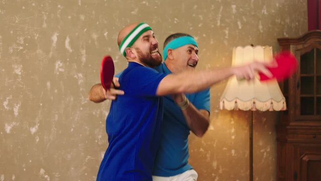 Excited happy and attractive father and son playing together like a team the table tennis or ping pong they catch all the balls with the racket and win