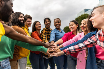 Young multiracial community of friends having fun stacking hands together outdoor 
