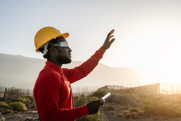 African engineer working with futuristic glasses on construction site - Technology and future...