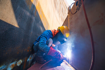 Male worker wearing protective clothing and repair welding industrial construction oil and gas or...