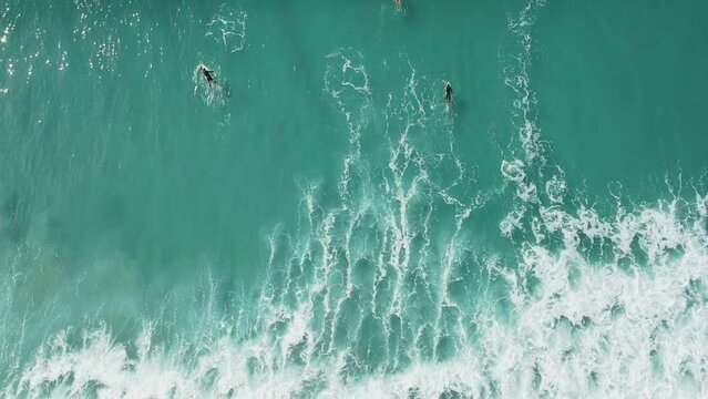 Surfers in turquoise ocean and waves. Aerial view