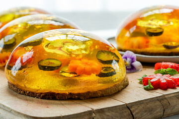 Lemon jelly globes with fresh fruit, edible flowers and gold flakes on pistachio biscuit - gourmet...