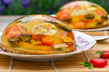 Lemon jelly globes with fresh fruit, edible flowers and gold flakes on pistachio biscuit - gourmet dessert