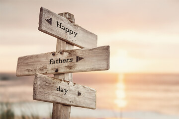 happy fathers day text quote on wooden crossroad signpost outdoors on beach with pink pastel sunset colors. Romantic theme.