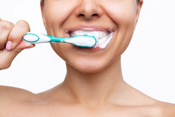 Cropped shot of a young smiling woman brushing her teeth with a toothbrush isolated on a white...