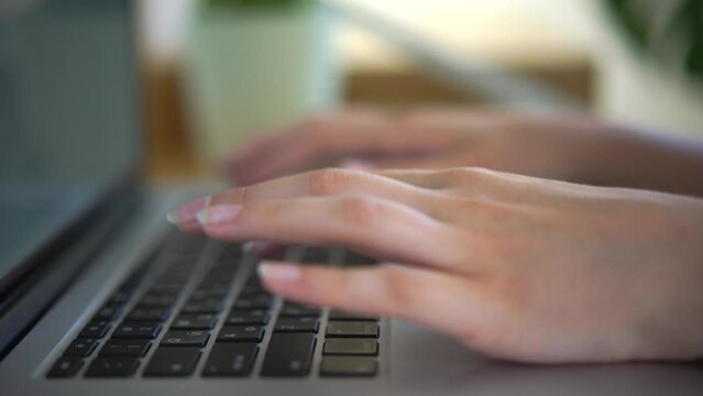 Female hands typing text messages on a laptop keyboard close-up. Busy business woman emailing a client using a digital wireless handheld device remotely. Business woman college university student