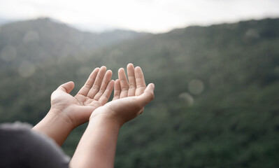 The two hands of a young man who prayed for hope from God Praise God concept. Pray, communicate. Mountain nature background. at sunrise