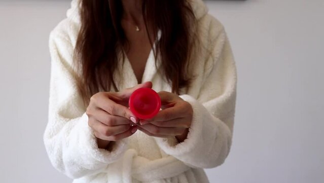 The woman throws out the new pads and leaves the menstrual cup in her hands.