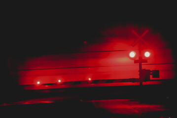 railway crossing at night.  Red lights moving train action shot.  