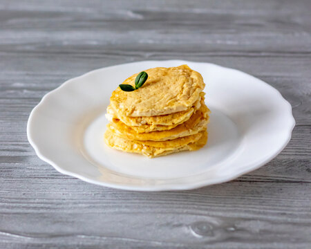 Mini omelets on a white plate on a gray wooden table.
