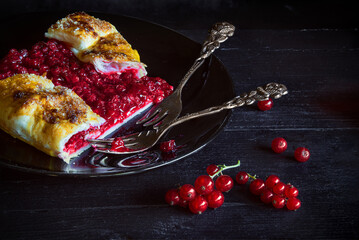 Red currant pie from recipe of Berry Galette with a cut slice and vintage forks - dark and moody