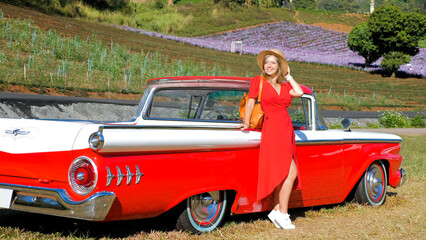 Happy woman in red dress enjoy sunset near country road and classic Vintage sports car. Romantic...