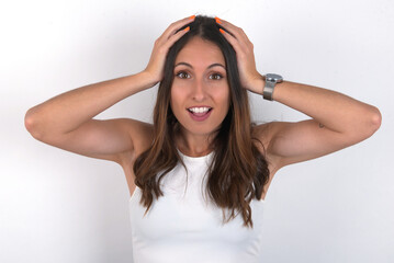 Cheerful overjoyed young beautiful caucasian woman wearing white Top over white background, reacts rising hands over head after receiving great news.