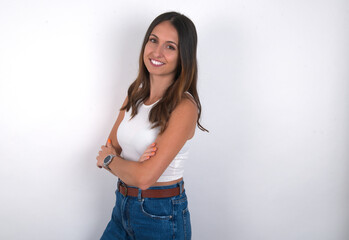 Portrait of young beautiful caucasian woman wearing white Top over white background, standing with folded arms and smiling