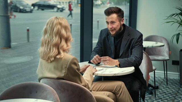 Handsome stylish couple laughing on a date in a coffee shop. They tell stories and jokes.