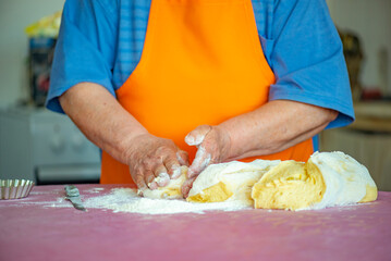 the grandmother kneads dough for Easter cakes on the table