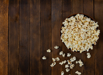 A bowl of delicious popcorn on a wooden table, top view, copy space
