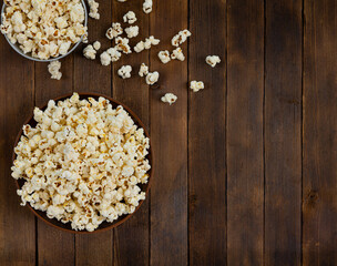 A bowl of delicious popcorn on a wooden table, top view, copy space