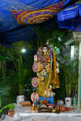 Idol of Goddess Saraswati being worshipped inside pandal , a temporary temple, at night. Colorful light on Hindu goddess. Howrah, West Bengal, India. Vertical image.
