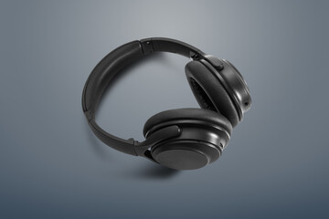 Fototapeta na wymiar Computer headphones. Black headphones on a dark grey background. The concept of listening to music, creating audio, music. Computer work, abstraction and minimalist style.