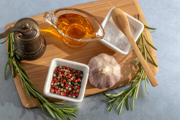 Set of spices for baking meat. Overhead view of ingredients. Top view of spices for baking meat: rosemary sprigs, garlic, mixture of 4 varieties of pepper, salt, olive oil