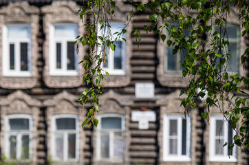 Fototapeta na wymiar Carved wooden trim facade. Old historic house. Russian architecture. Chopped house with carved wooden architraves. Apple blossom. Tomsk, Russia