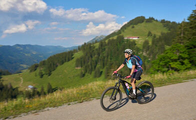 pretty senior woman riding her electric mountain bike in the Allgaeu mountains above Oberstaufen , Allgau Alps, Bavaria Germany

