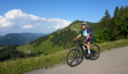 Obraz premium pretty senior woman riding her electric mountain bike in the Allgaeu mountains above Oberstaufen , Allgau Alps, Bavaria Germany 