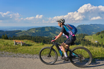 pretty senior woman riding her electric mountain bike in the Allgaeu mountains above Oberstaufen ,...